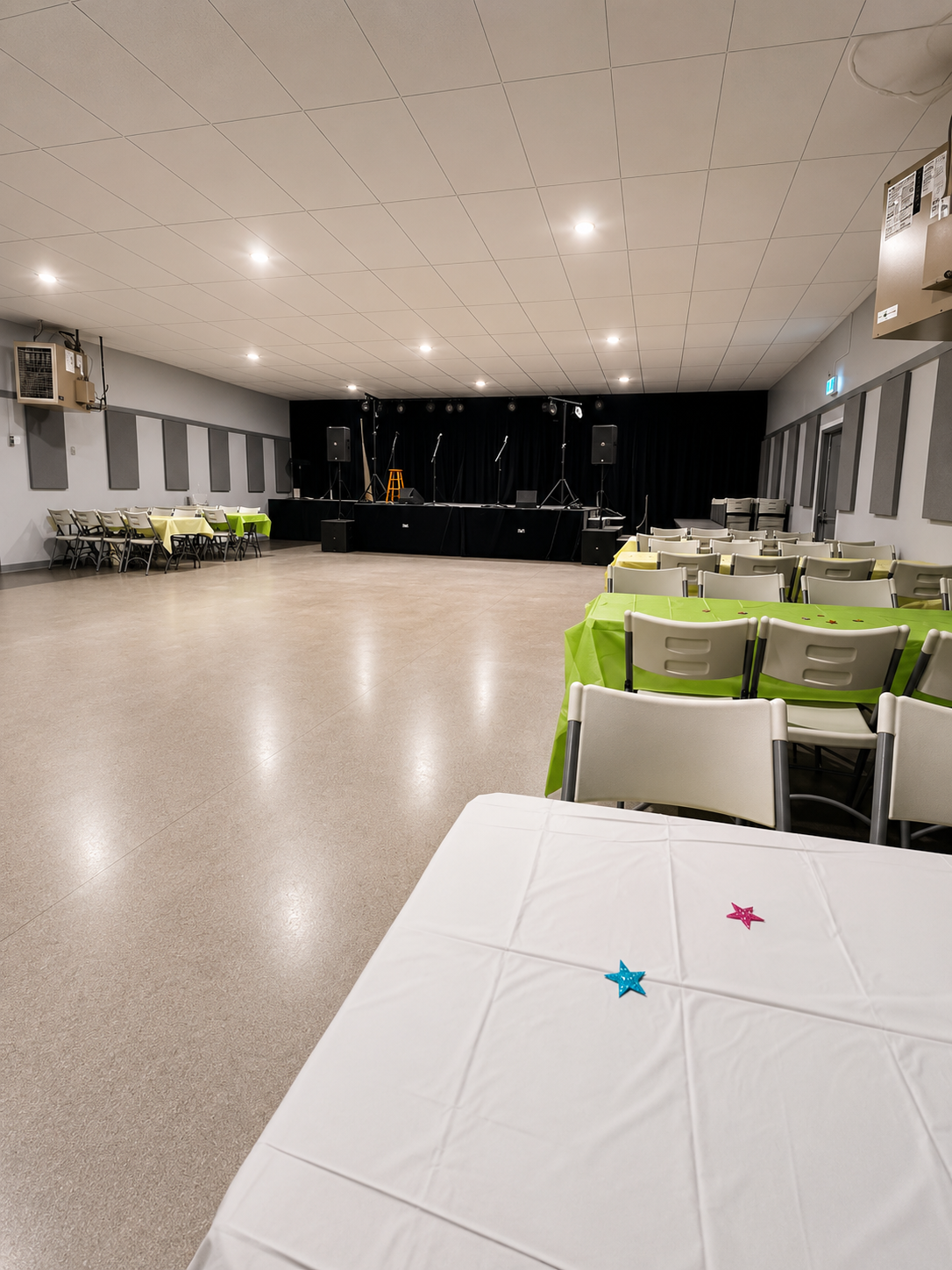 Tables set up inside Montney Hall with stage in background